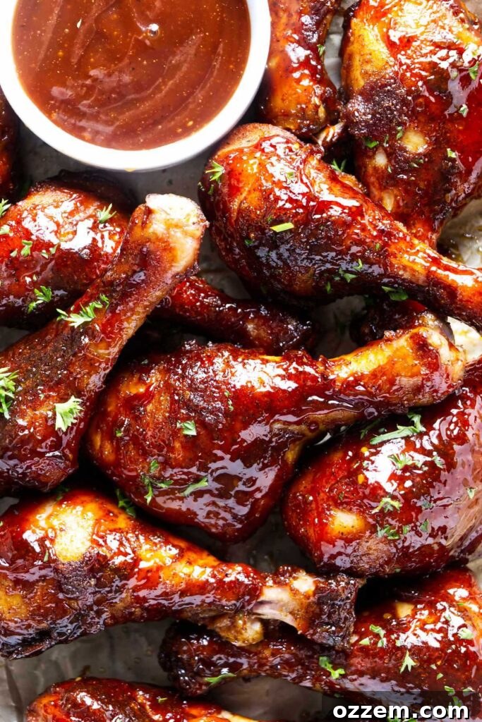 Smoked Chicken Drumsticks Recipe for Tender, Smoky Flavor 2 A pile of smoked chicken drumsticks coated in BBQ sauce on a serving platter.