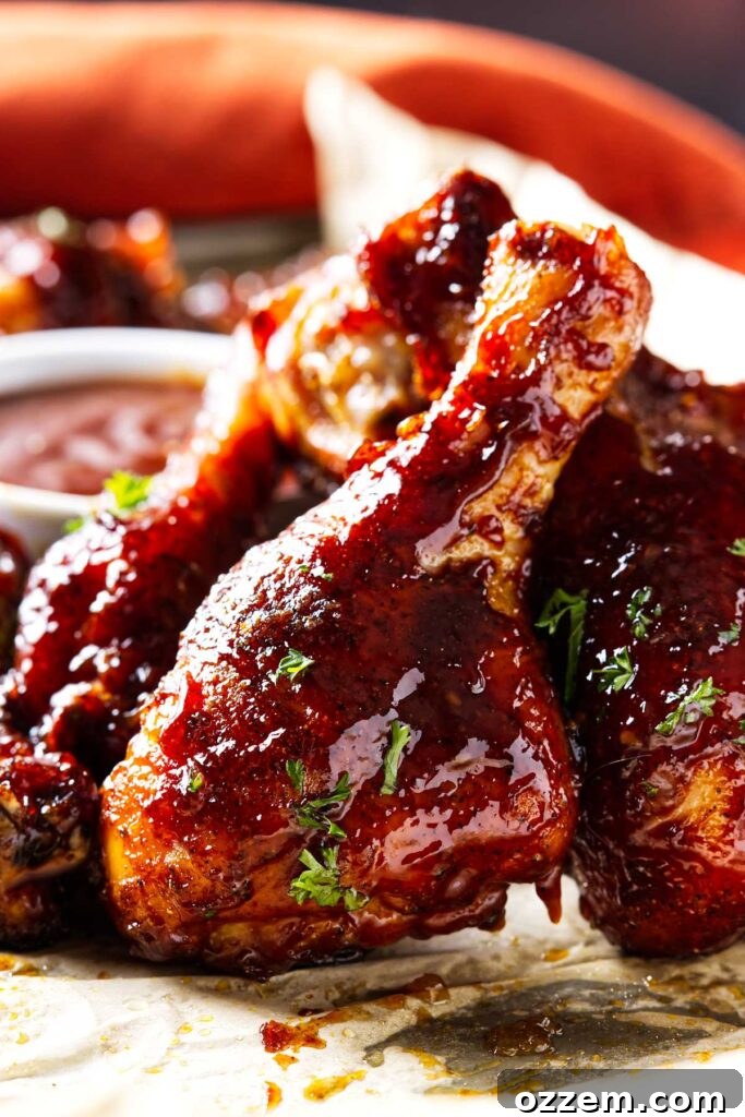 Smoked Chicken Drumsticks Recipe for Tender, Smoky Flavor 6 A smoked chicken leg sprinkled with fresh parsley in front of a dish of bbq sauce.