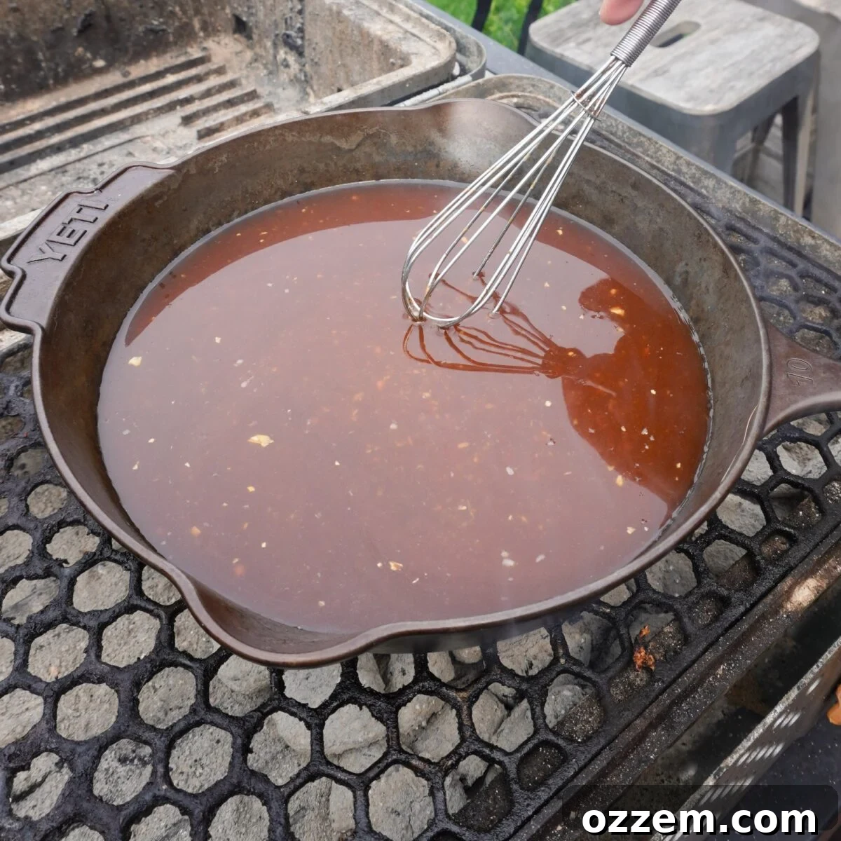 Bourbon sauce in a cast iron skillet over a charcoal grill.