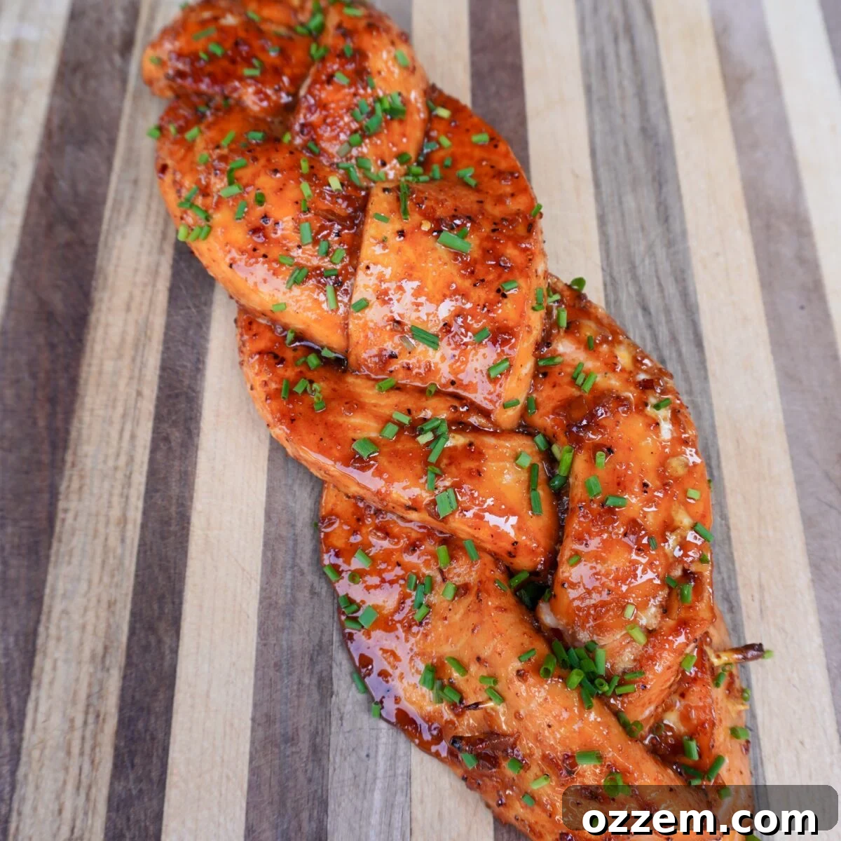 Smoked braided salmon on the cutting board topped with chives.