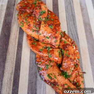 Smoked braided salmon on the cutting board topped with chives.