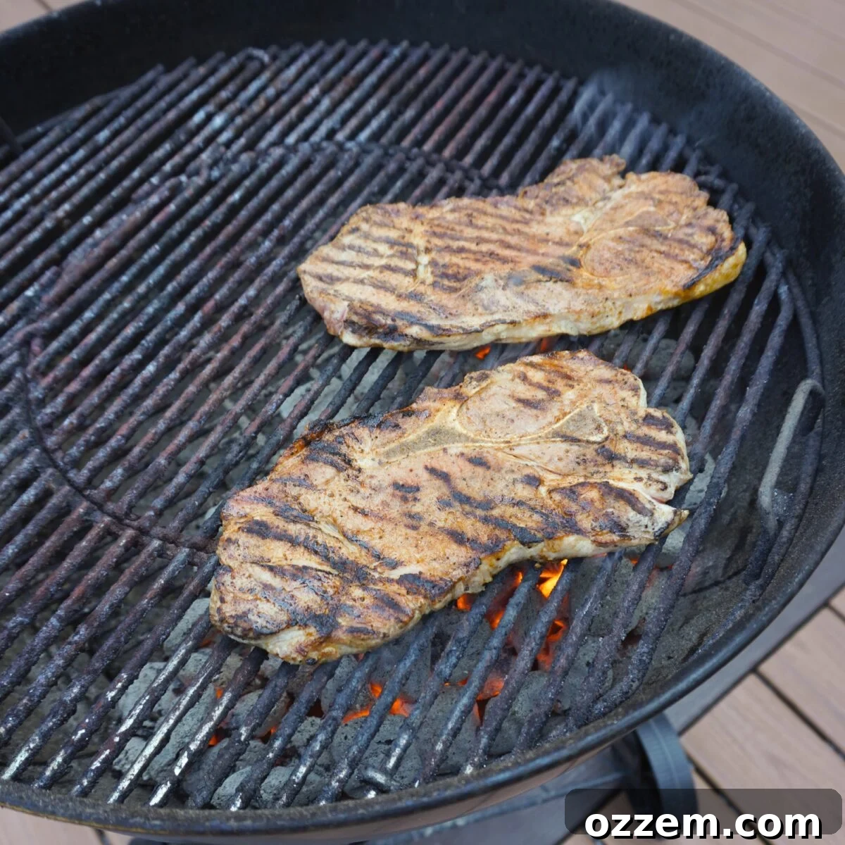 Grilled Savory Pork steaks over direct heat on a Weber Kettle Grill.