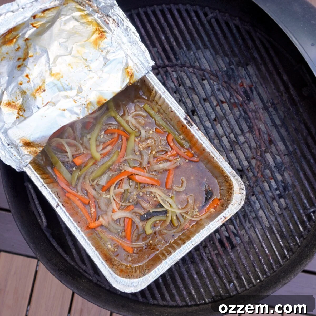 Braised pork steaks in aluminum pan over the grill.