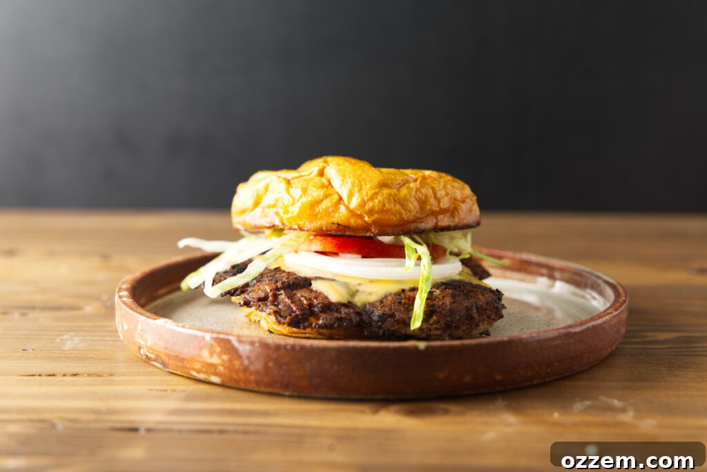 Blackstone Smash Burgers with Perfectly Crispy Edges 5 Blackstone smash burger plated on a brown ceramic plate and resting on a wood butcher block.