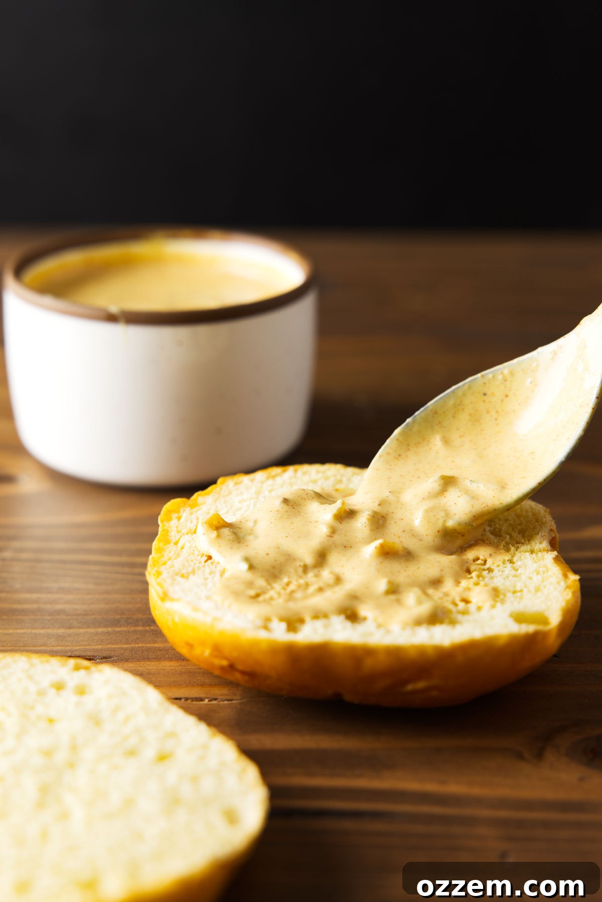 Spreading smash burger sauce on burger bun with spoon.