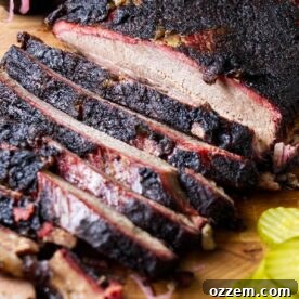 A smoked brisket on a cutting board next to pickles.