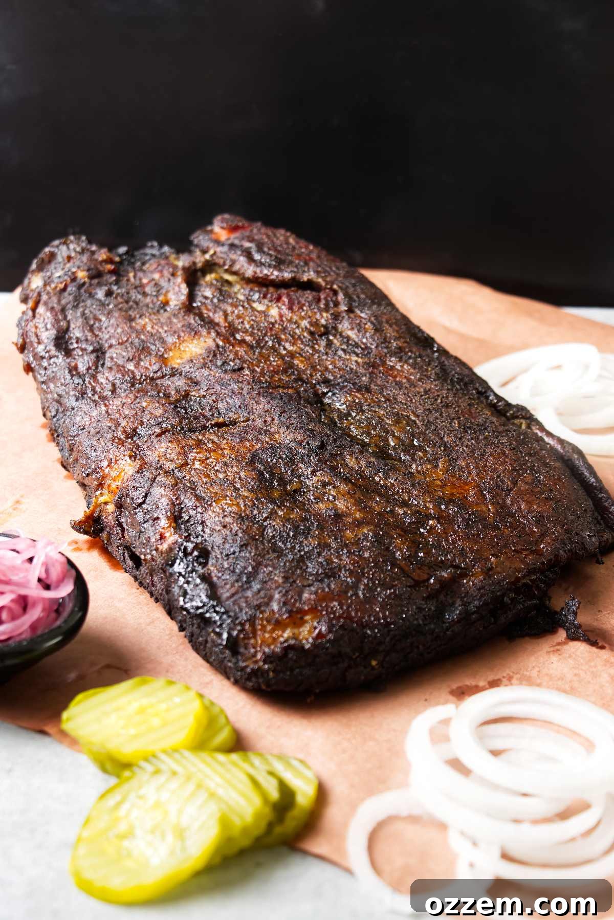 A smoked brisket on peach paper next to pickled onion.