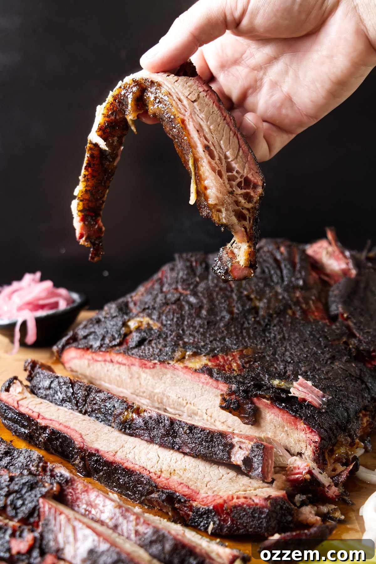 Hand holding a slice of smoked brisket.