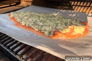 Smoky Pellet Grill Salmon Recipe 12 Fillet of salmon with compound butter spread on top and sitting on the grill grates.