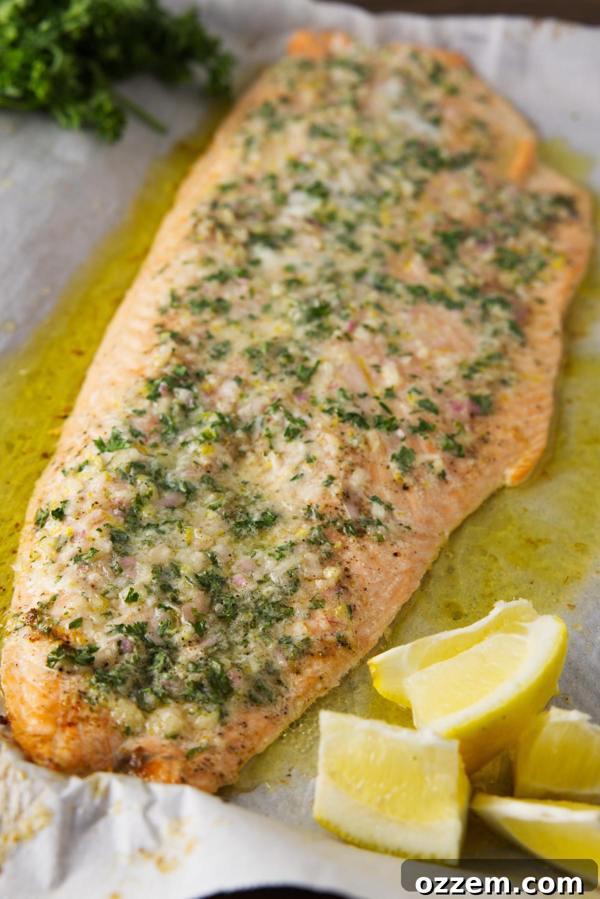 Smoky Pellet Grill Salmon Recipe 3 Salmon resting on sheet pan with lemon wedges and parsley.