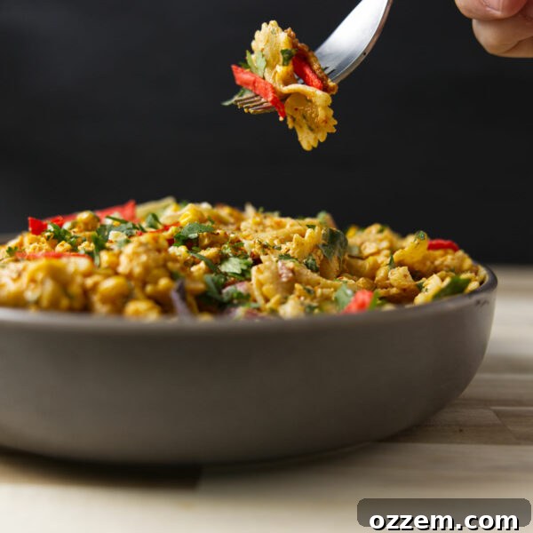 Fork shot with a bite of elote Mexican street corn pasta salad above a heaping full bowl.
