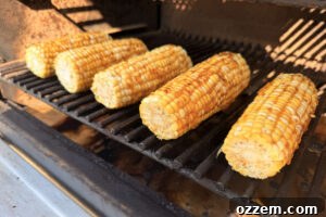 Corn on the cob smoking directly on the pellet grill grates.