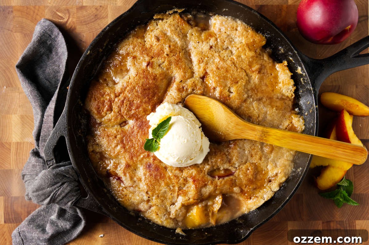 A wooden spoon and a scoop of ice cream on top of a hot peach cobbler.