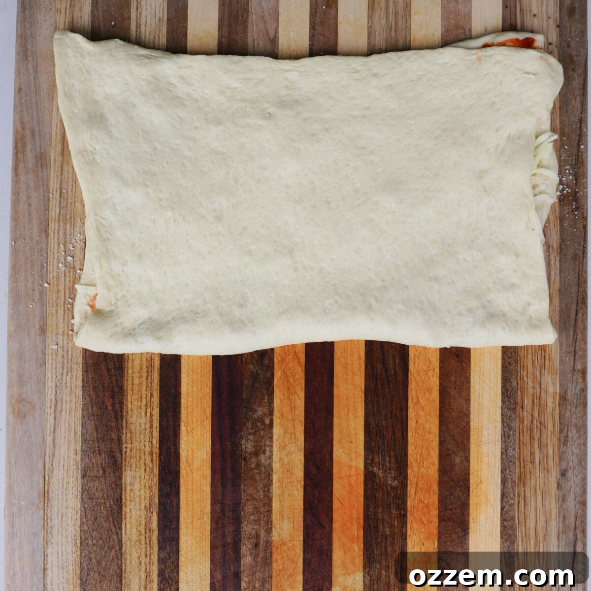 Homemade Cheesy Pizza Twist Sticks 5 Folded pizza dough over toppings.